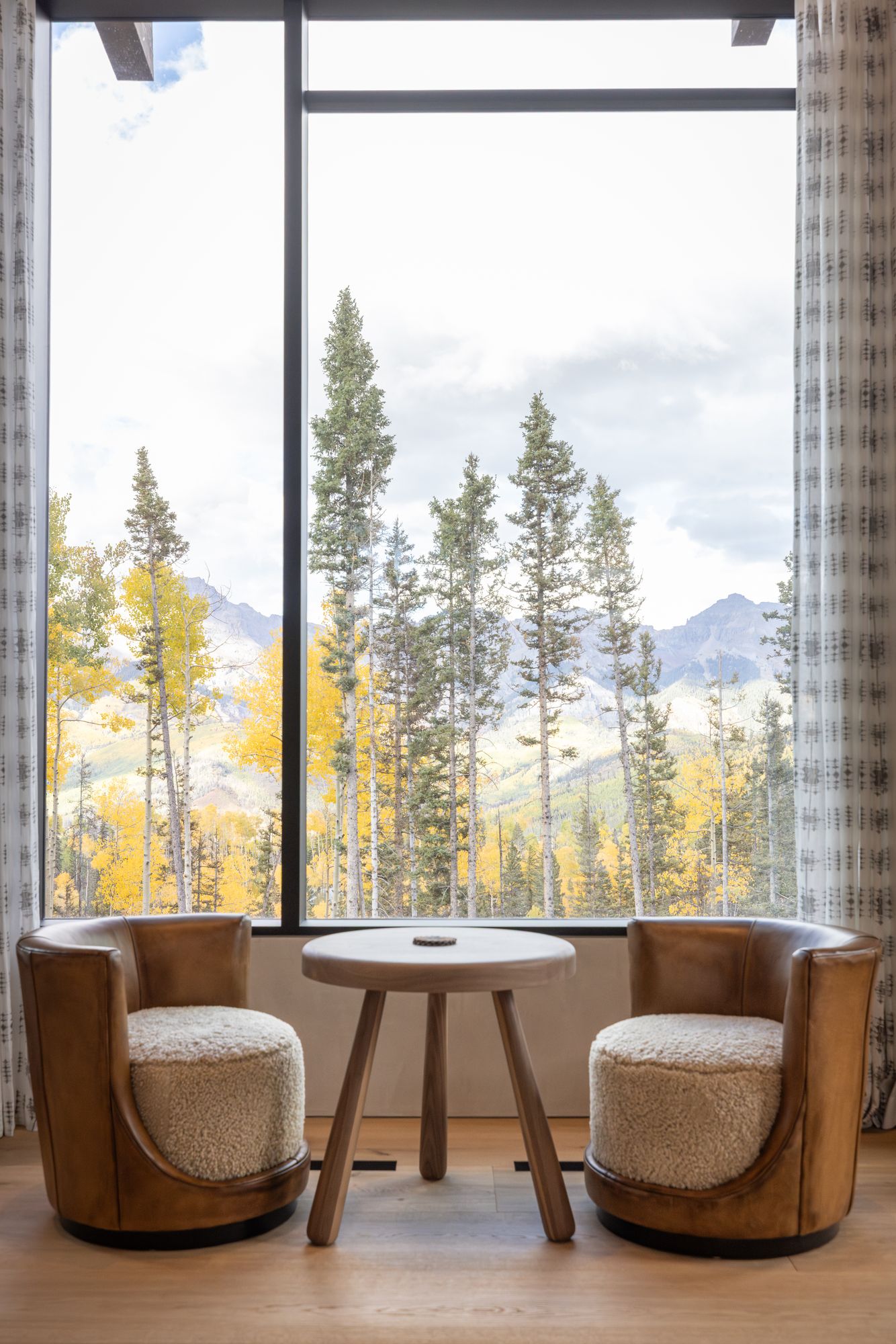 White Oak House, interior design photography in Telluride, CO: leather chairs at a window framing aspens and peaks