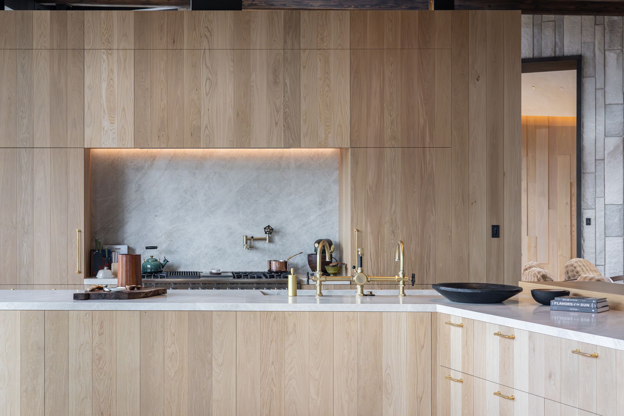 White oak kitchen with stone backsplash and brass fixtures, photographed for an interior designer in Telluride, Colorado