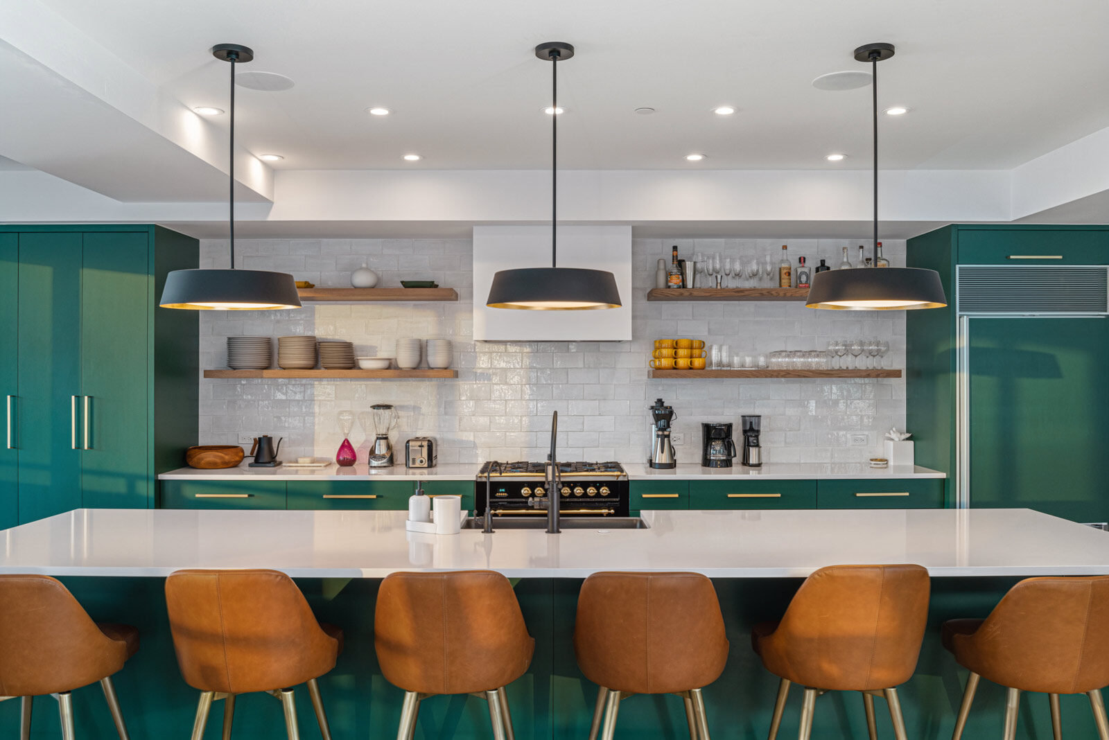 Kitchen with deep green cabinetry, white tile, open wood shelving and leather stools. Sky High at the Plaza, Mountain Village, CO