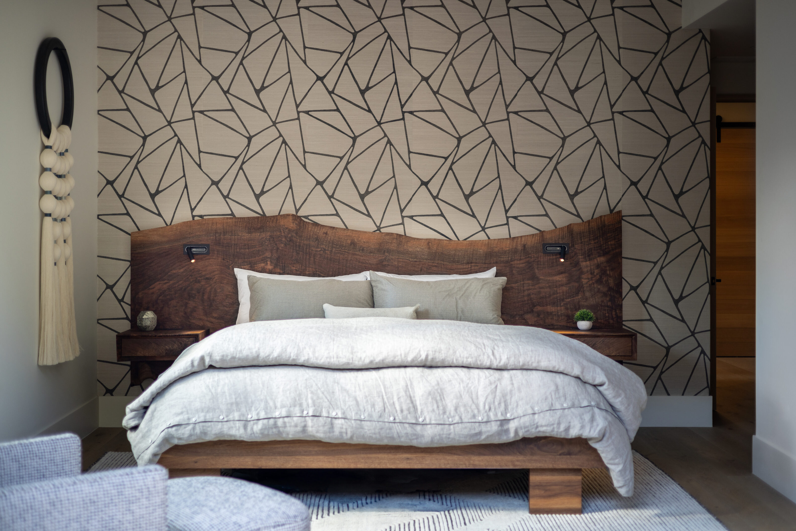 Bedroom with a live-edge walnut headboard against geometric wallpaper. Weathered Stone, Ouray, CO