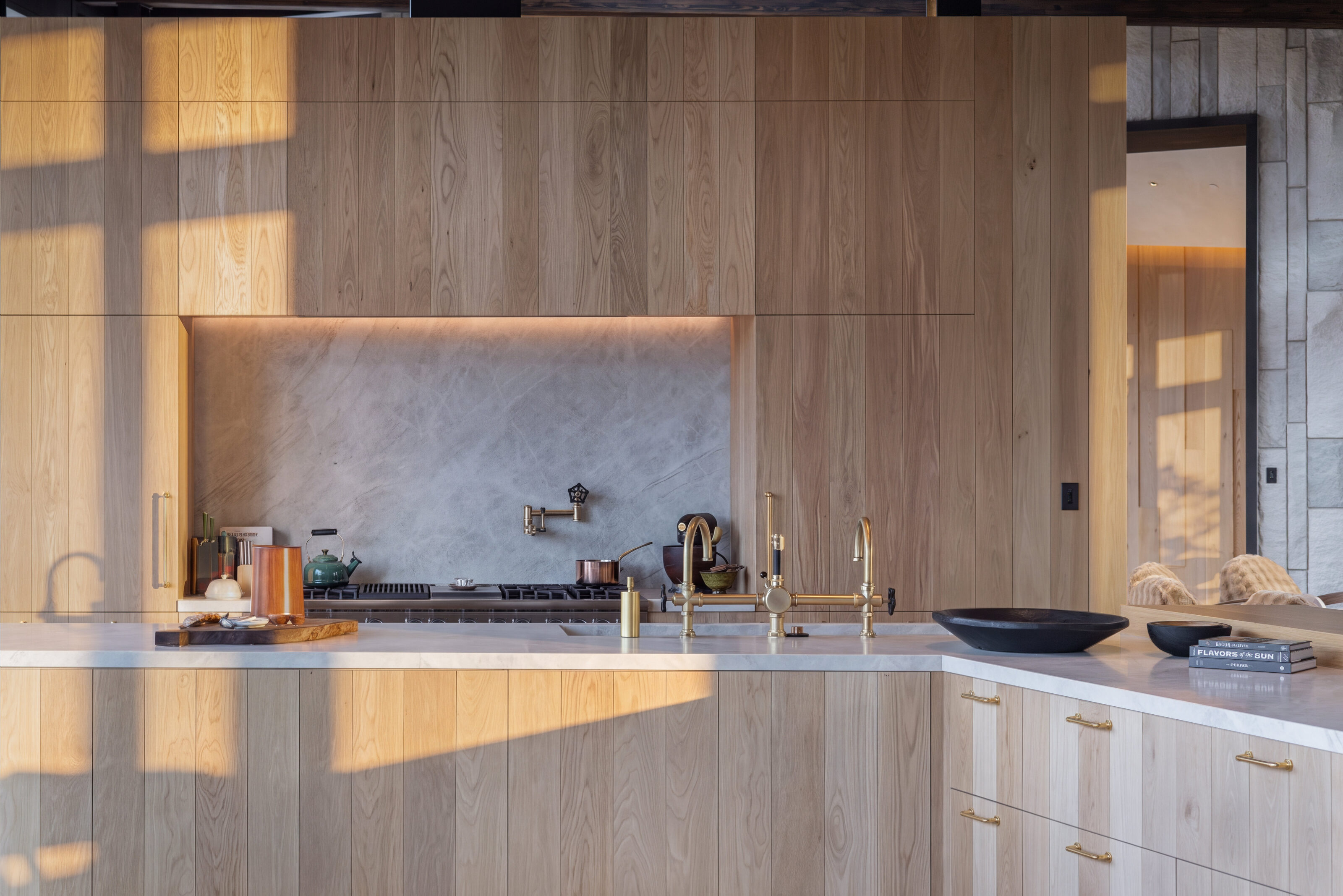 White oak kitchen wall with a stone backsplash in raking afternoon light. White Oak House, Telluride, CO